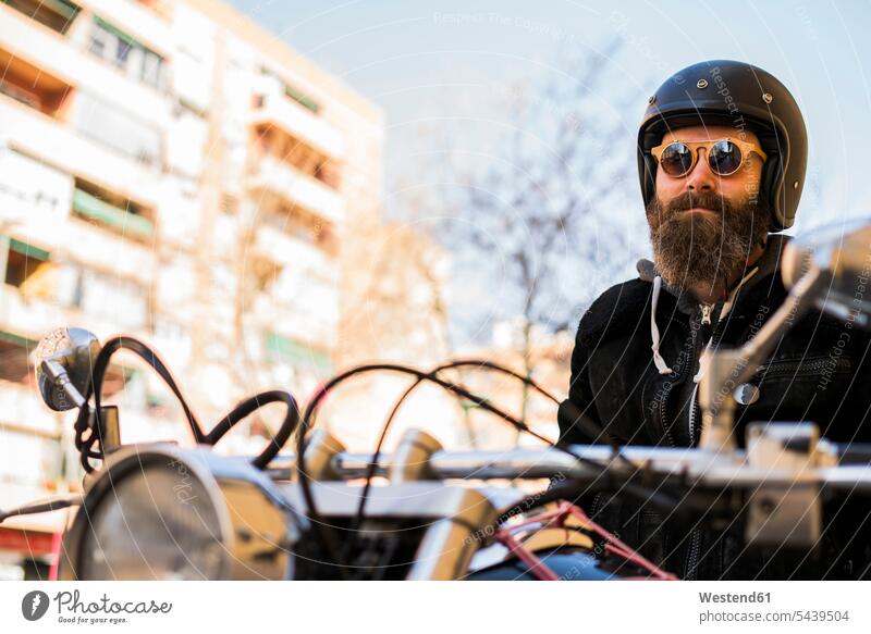 Portrait of bearded biker wearing helmet and sunglasses sitting on his motorcycle motorcyclist people persons human being humans human beings men males