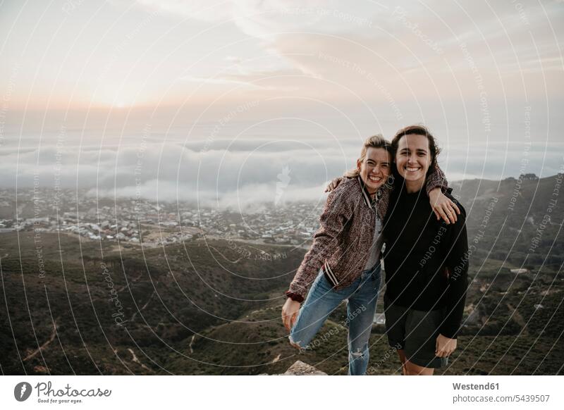 South Africa, Cape Town, Kloof Nek, portrait of two happy women embracing at sunset embrace Embracement hug hugging woman females girlfriend Girlfriends