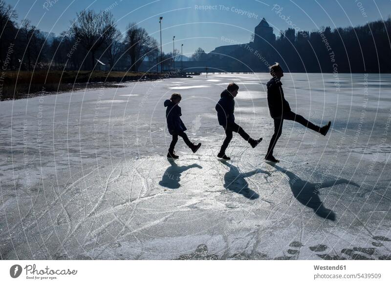 Three children playing on icy surface playful leisure free time leisure time shadow shadows Shades shadow play walking going sunlight Sunlit bonding community