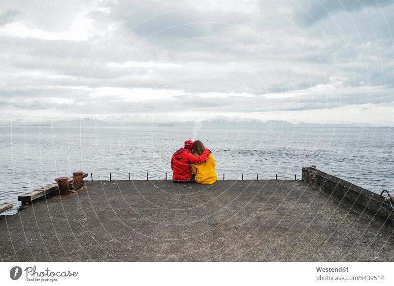 Iceland, North of Iceland, back view of couple sitting on jetty looking at view eyeing View Vista Look-Out outlook twosomes partnership couples landing stage
