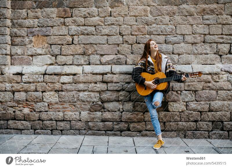 Red-haired woman playing the guitar in the city music females women musician female musician musicians redheaded red hair red hairs red-haired smiling smile