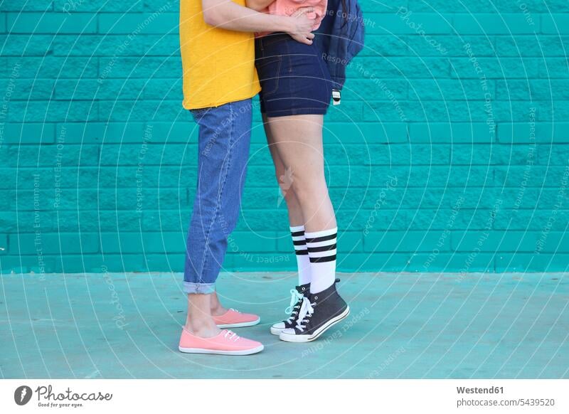 Young couple kissing in front of blue brick wall, partial view twosomes partnership couples people persons human being humans human beings kisses leg legs
