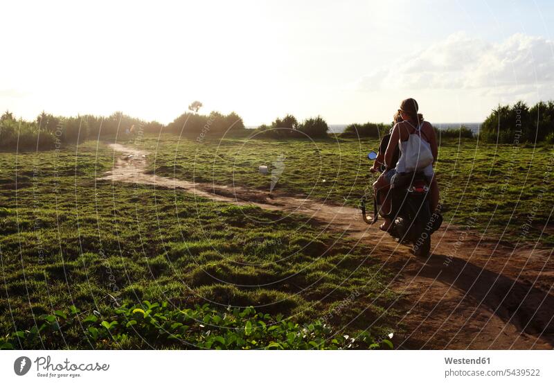 Indonesia, Bali, Nusa Lembongan, two persons driving on a scooter relaxation relaxing meadow meadows Incidental people dirt track field paths recreation nature