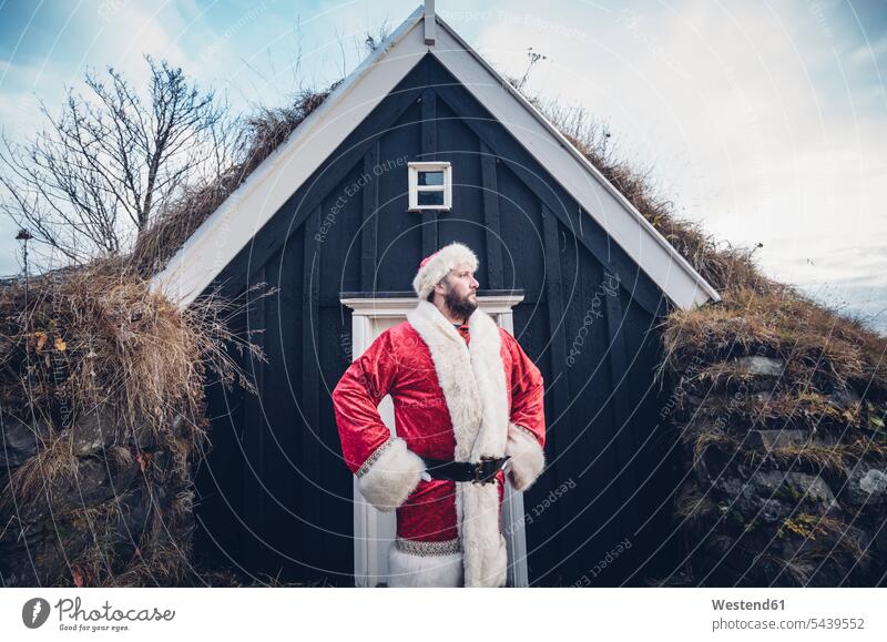 Iceland, Santa Claus standing in front of cabin looking at distance cabins Father Christmas X-Mas yule Xmas X mas celebration Red-Letter Day Festive Day