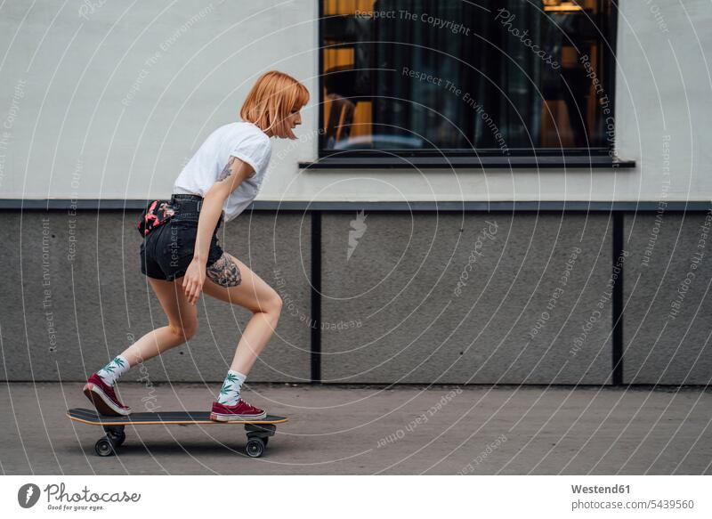 Young woman riding carver skateboard on the sidewalk pavement Side Walk females women Skate Board skateboards Adults grown-ups grownups adult people persons