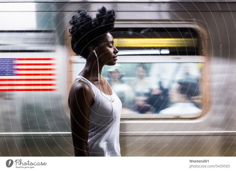 USA, New York City, Manhattan, woman with earphones on subway station platform females women Adults grown-ups grownups adult people persons human being humans