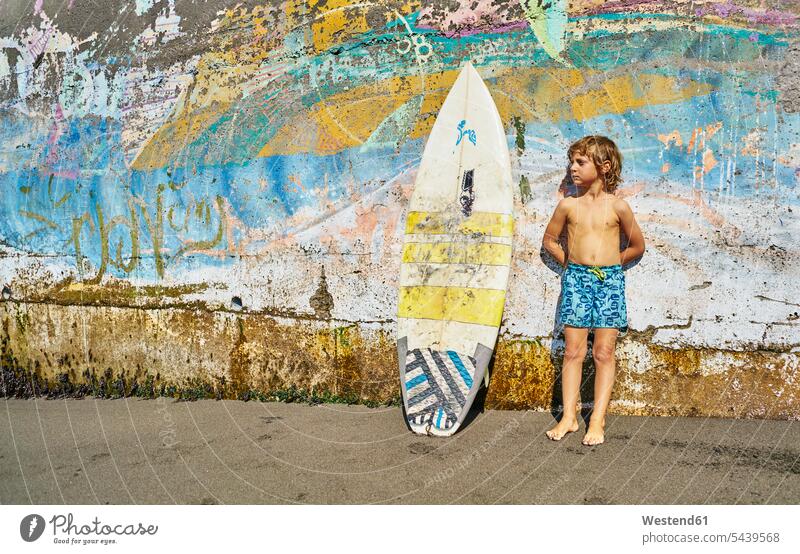 Chile, Pichilemu, boy standing at a colorful wall with surfboard multi-coloured multicoloured multi colored Multi Coloured surfboards walls boys males colours