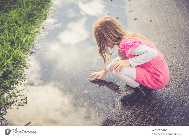 Little girl playing with water of a puddle Landshut day daytime daylight shot day shots daylight shots casual casual wear leisure wear casual clothing