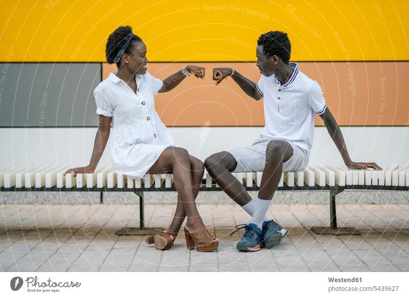 Smiling young woman giving teenage boy a fist bump human human being human beings humans person persons African black black ethnicity coloured Afro European 2