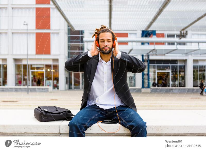Portrait of young businessman with dreadlocks listening music with headphones and cell phone headset Businessman Business man Businessmen Business men