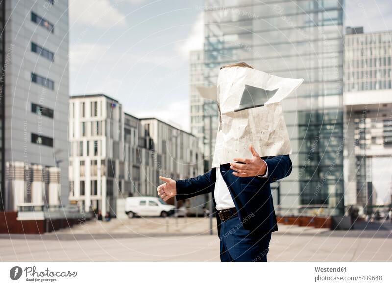 Newspaper covering businessman's face in the city town cities towns Businessman Business man Businessmen Business men outdoors outdoor shots location shot