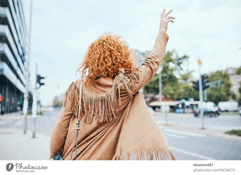 Redheaded woman hailing a taxi in the street redheaded red hair red hairs red-haired hailing taxi road streets roads young women young woman waving wave people