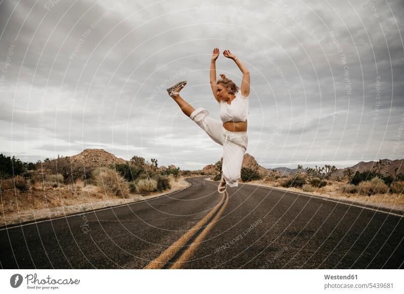 Woman jumping on road, Joshua Tree National Park, California, USA (value=0) human human being human beings humans person persons caucasian appearance