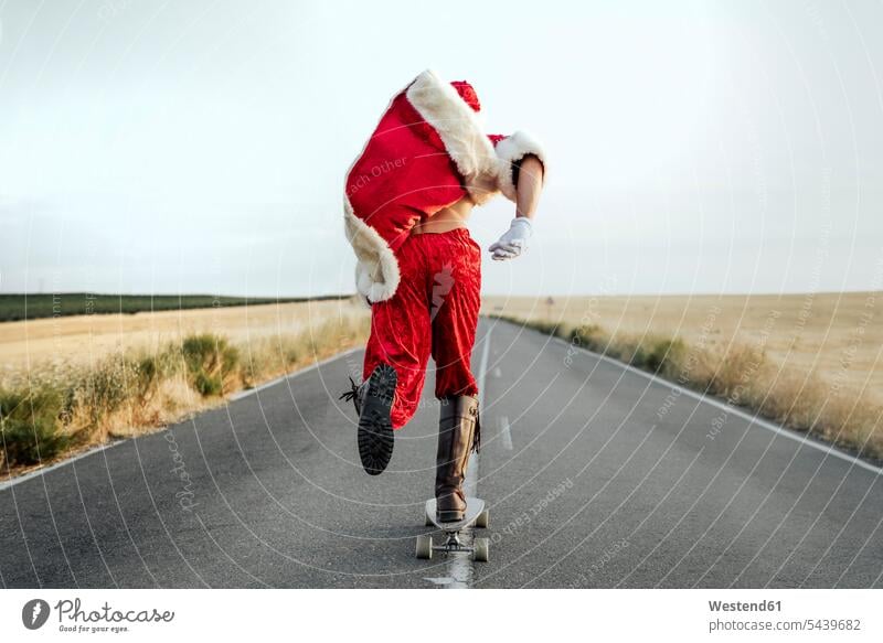 Santa Claus riding on longboard on country road human human being human beings humans person persons caucasian appearance caucasian ethnicity european 1