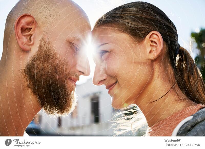 Young couple in love face to face at backlight twosomes partnership couples happiness happy people persons human being humans human beings touching head to head