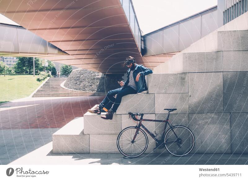 Spain, Bilbao, Man with smartphone and headphone, racing cycle caucasian caucasian ethnicity caucasian appearance european outdoors outdoor shots location shot