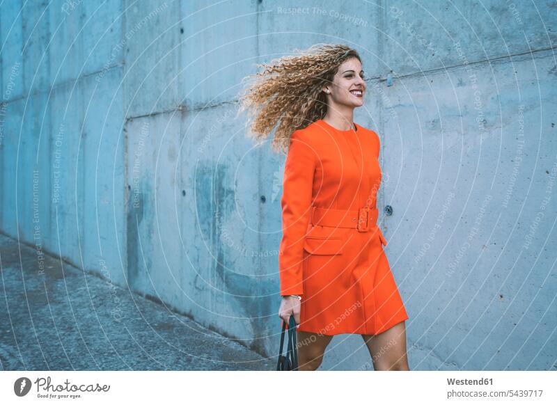 Happy young woman wearing red dress walking along street human human being human beings humans person persons caucasian appearance caucasian ethnicity european