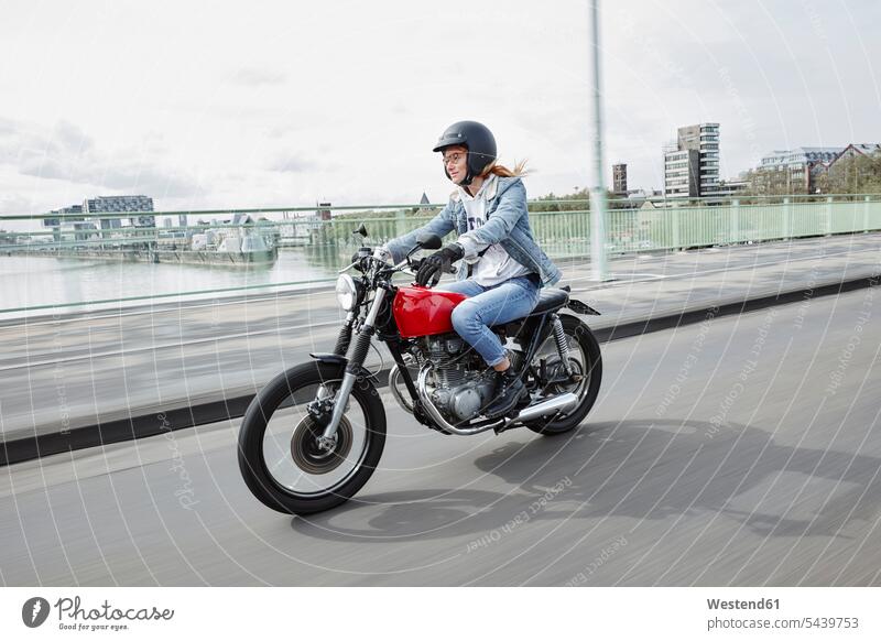 Germany, Cologne, young woman riding motorcycle on bridge motorbike Motor Cycle driving drive bridges females women motor vehicle road vehicle road vehicles