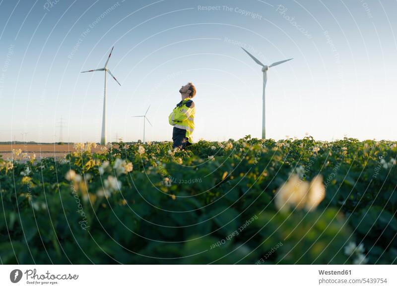 Engineer standing in a field at a wind farm Field Fields farmland wind park engineer engineers wind power plant wind turbine wind turbines wind energy