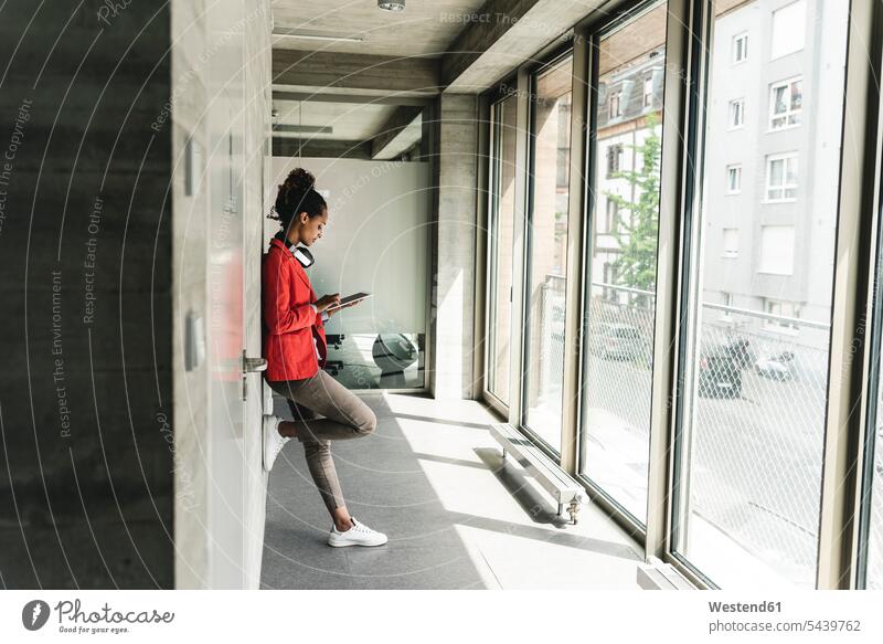 Young woman with headphones standing in corridor, using digital tablet creative professional Creative People creatives Creative Occupation