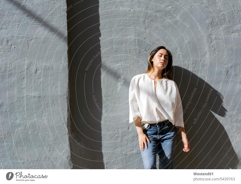 Portrait of young woman leaning against grey wall walls gray females women portrait portraits colour colours Adults grown-ups grownups adult people persons