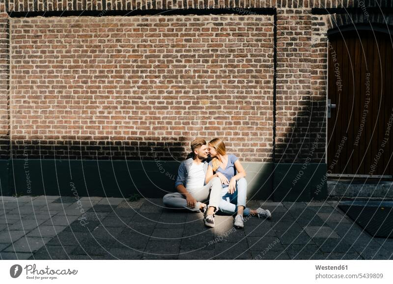 Netherlands, Maastricht, young couple having a break in the city sitting on sidewalk town cities towns pavement Side Walk twosomes partnership couples Seated