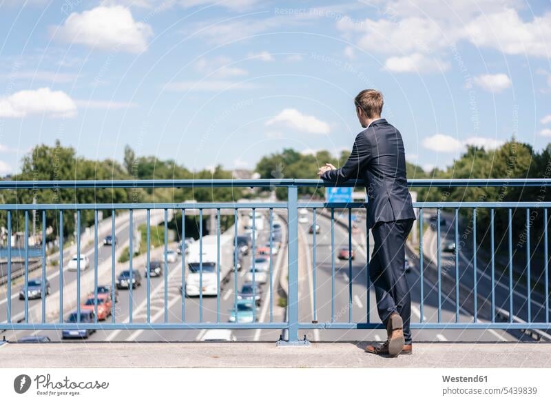 Businessman standing on a bridge over a motorway car automobile Auto cars motorcars Automobiles Business man Businessmen Business men traffic motor vehicle