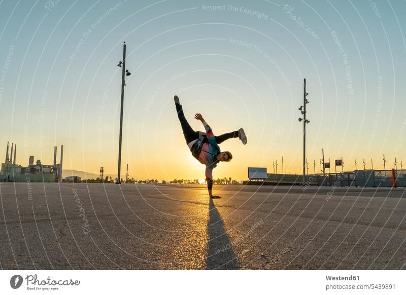 Acrobat doing handstand in the city at sunrise on one arm acrobat acrobats equilibrists handstands sun rise sunrises athlete Sportspeople Sportsman Sportsperson