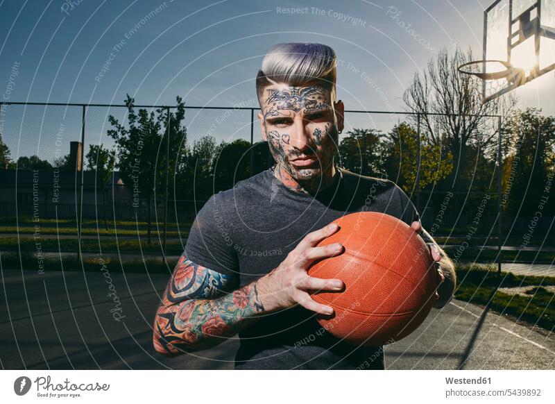 Portrait of tattooed young man with basketball on court portrait portraits sports field sports fields tattoos men males basketballs body art Body Adornment