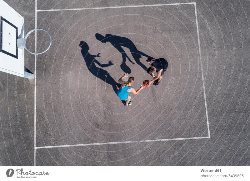 Young man and woman playing basketball, aerial view sport sports Basketball basketball hoop backboard basketball hoops line lines opponent opponents adversary