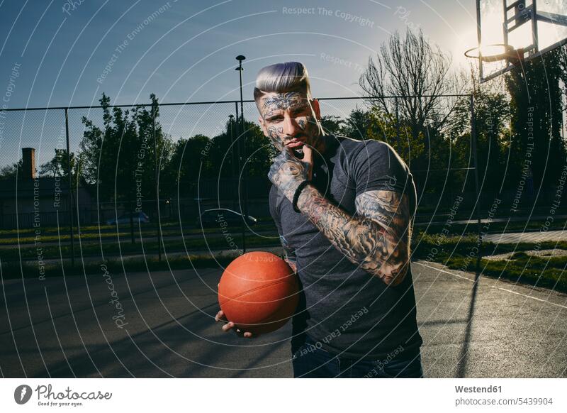 Portrait of tattooed young man with basketball on court sports field sports fields portrait portraits men males tattoos basketballs Adults grown-ups grownups