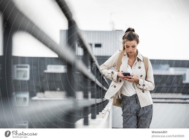Young businesswoman using smartphone in he city Smartphone iPhone Smartphones young on the move on the way on the go on the road urban urbanity use Railing