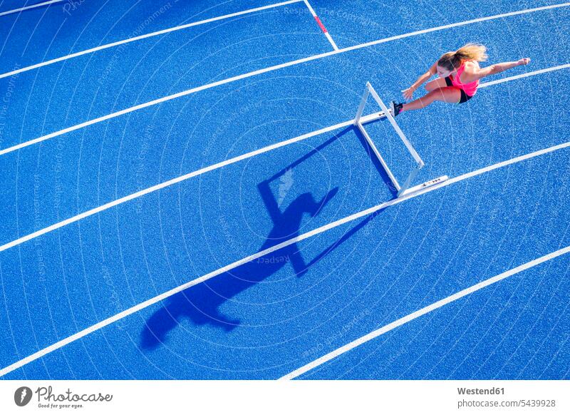 Top view of female runner crossing hurdle on tartan track athletics track and field athletics athletic sports Hurdle barrier barriers Hurdles athlete