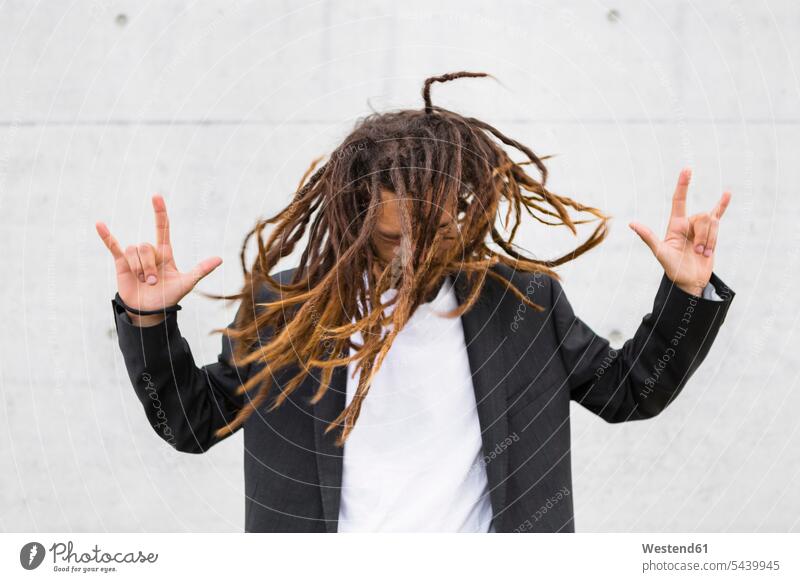 Young businessman tossing his dreadlocks showing Rock And Roll Sign men males Adults grown-ups grownups adult people persons human being humans human beings
