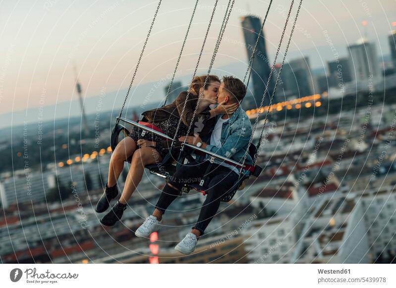 Young couple in love, riding chairoplane on a fairground young couple young couples young twosome young twosomes romance Romancing kissing kisses funfairs