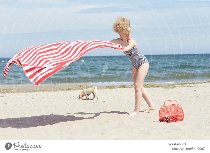 Young woman with blowing beach towel at seaside beaches Beach Towel females women Adults grown-ups grownups adult people persons human being humans human beings