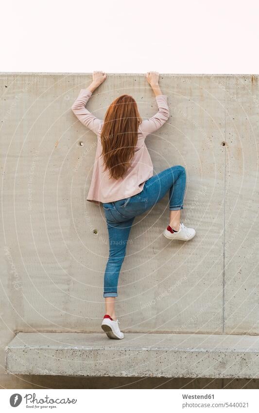 Young redheaded woman climbing on concrete wall benches in the evening successful free Liberty free time leisure time Force Power Strengthy strong Incentive