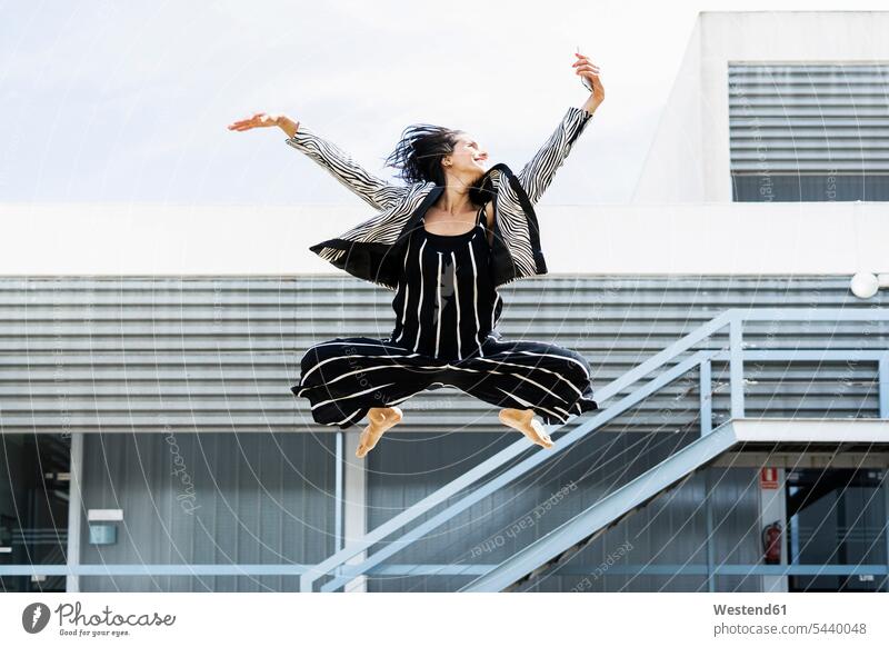 Female ballet dancer jumping with a smartphone and taking a selfie in front of an office building female ballet dancer ballerina ballerinas danseuse