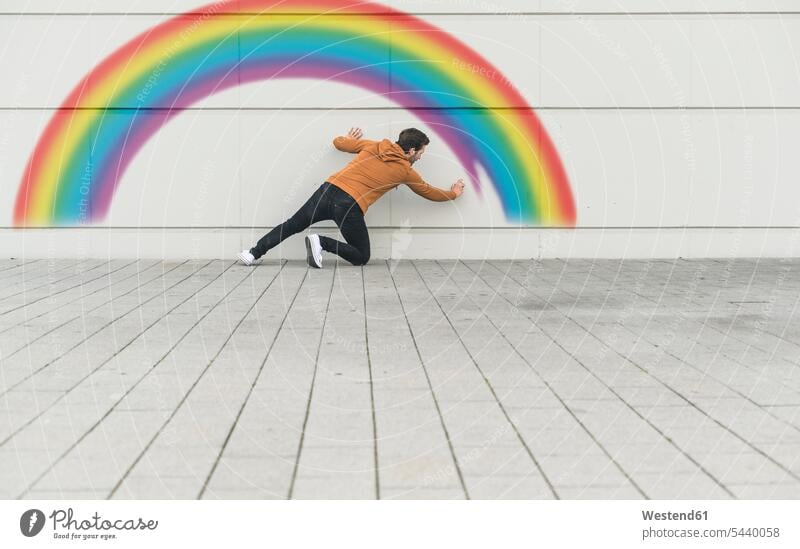 Digital composite of young man painting a rainbow at a wall human human being human beings humans person persons caucasian appearance caucasian ethnicity