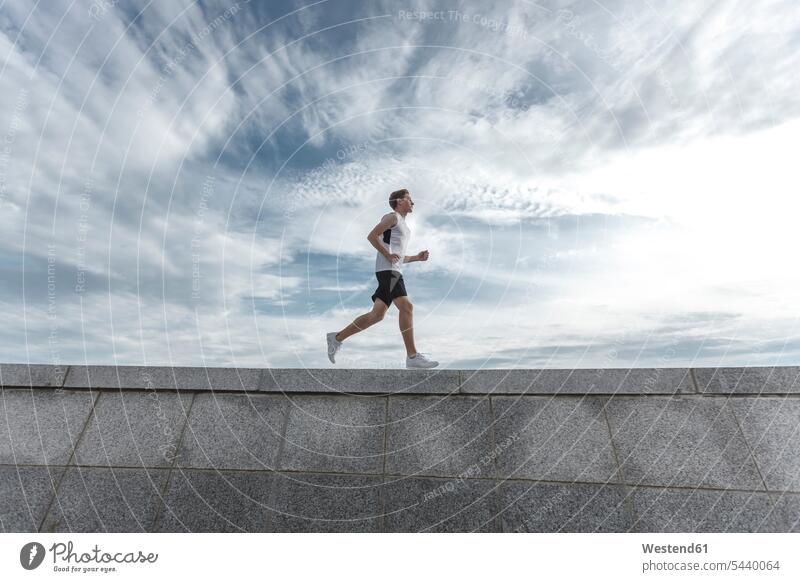 Young man running on wall walls exercising exercise training practising men males Jogging Adults grown-ups grownups adult people persons human being humans
