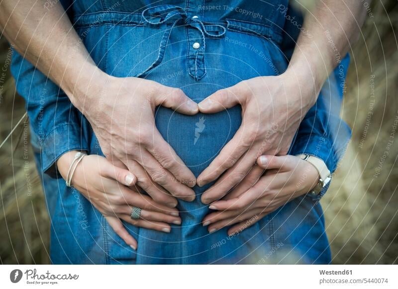 Hand of man forming heart on the belly of his pregnant girlfriend caucasian european caucasian ethnicity caucasian appearance Anticipation hopeful expectation