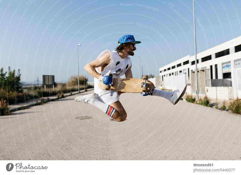 Sportive man jumping above ground with skateboard on hands holding sportive sporting sporty athletic men males Trick skateboarding Boarding skateboarder skater