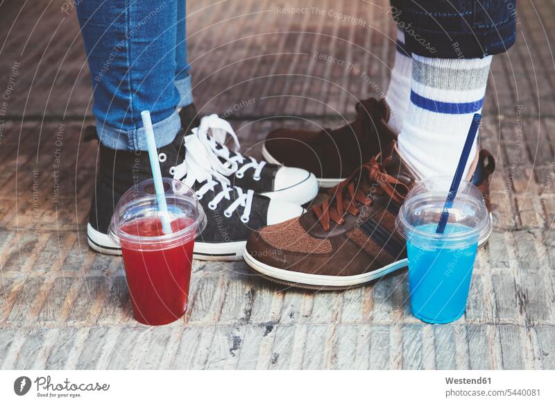 Plastic cups with soft drinks standing besides feet of young couple caucasian caucasian ethnicity caucasian appearance european leg legs human leg human legs