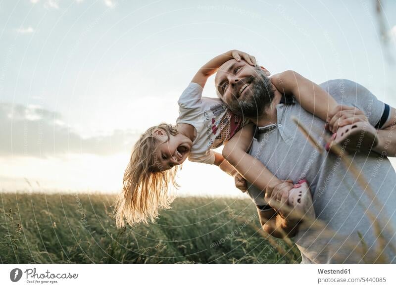 Mature man playing with his little daughter in nature men males daughters natural world Adults grown-ups grownups adult people persons human being humans