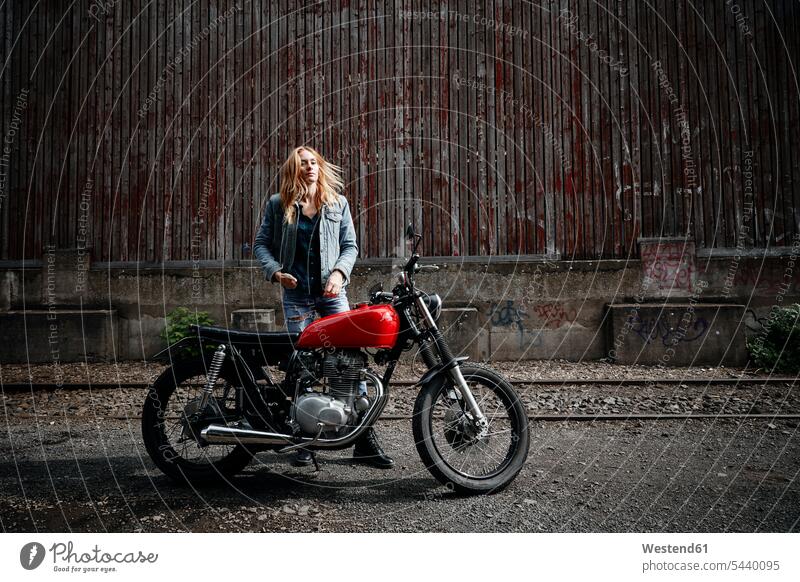 Confident young woman standing next to motorcycle motorbike Motor Cycle females women confidence confident motor vehicle road vehicle road vehicles