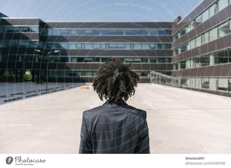 Rear view of businessman with dreadlocks standing outside office human human being human beings humans person persons African black black ethnicity coloured 1
