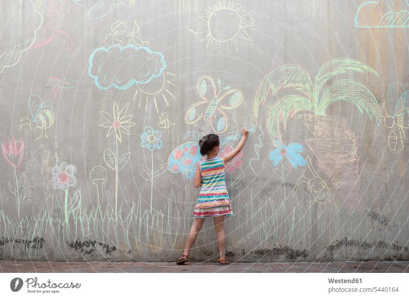 Girl drawing colourful pictures with chalk on a concrete wall sketching girl females girls multi-coloured multicoloured multi colored Multi Coloured colorful
