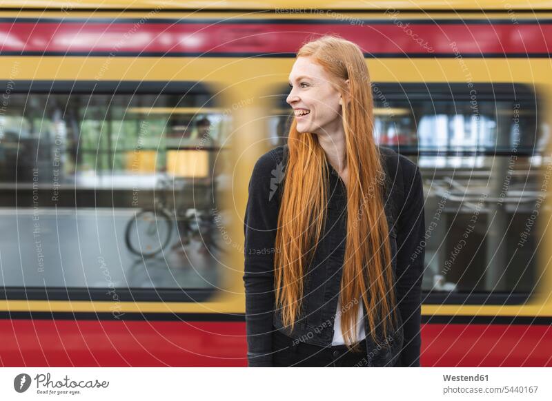 Laughing redheaded young woman waiting at platform, Berlin, Germany smile delight enjoyment Pleasant pleasure Contented Emotion pleased stand free time