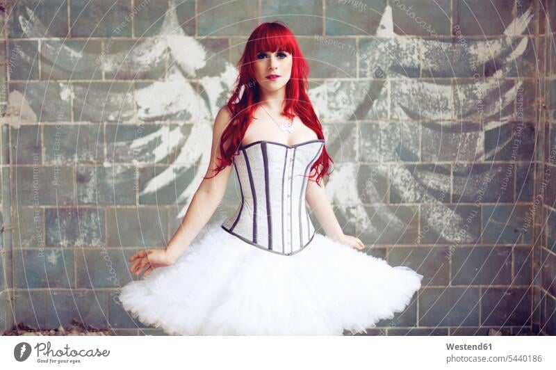 Portrait of woman with red hair and ballerina dress standing in front of wall with angle wings graffiti caucasian european caucasian ethnicity