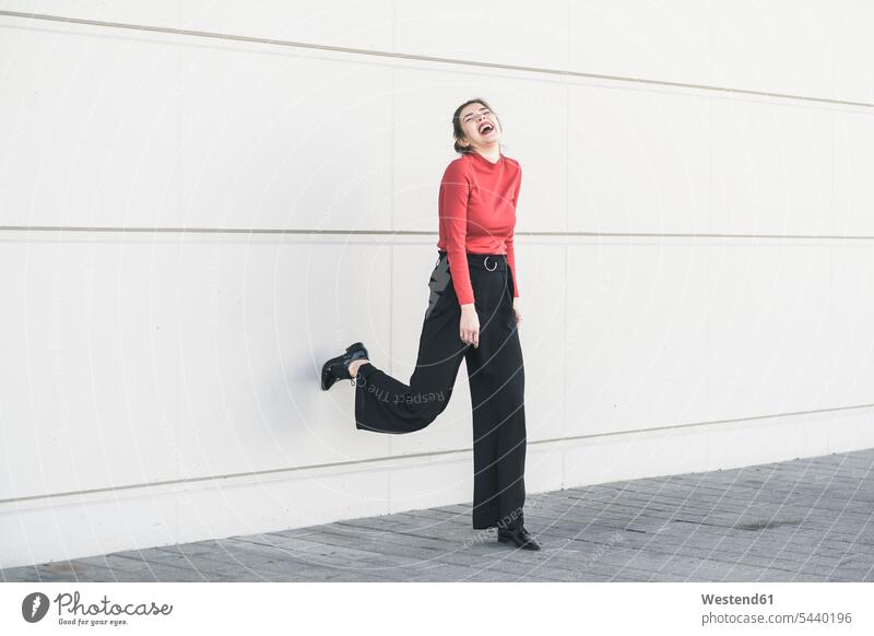 Laughing young woman leaning against a wall standing elegant chic elegance stylishly classy walls happiness happy laughing Laughter females women style positive